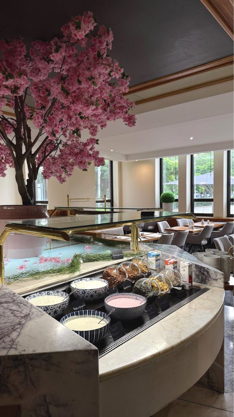 Curved breakfast buffet with yogurt bowls, cereals and restaurant seating.